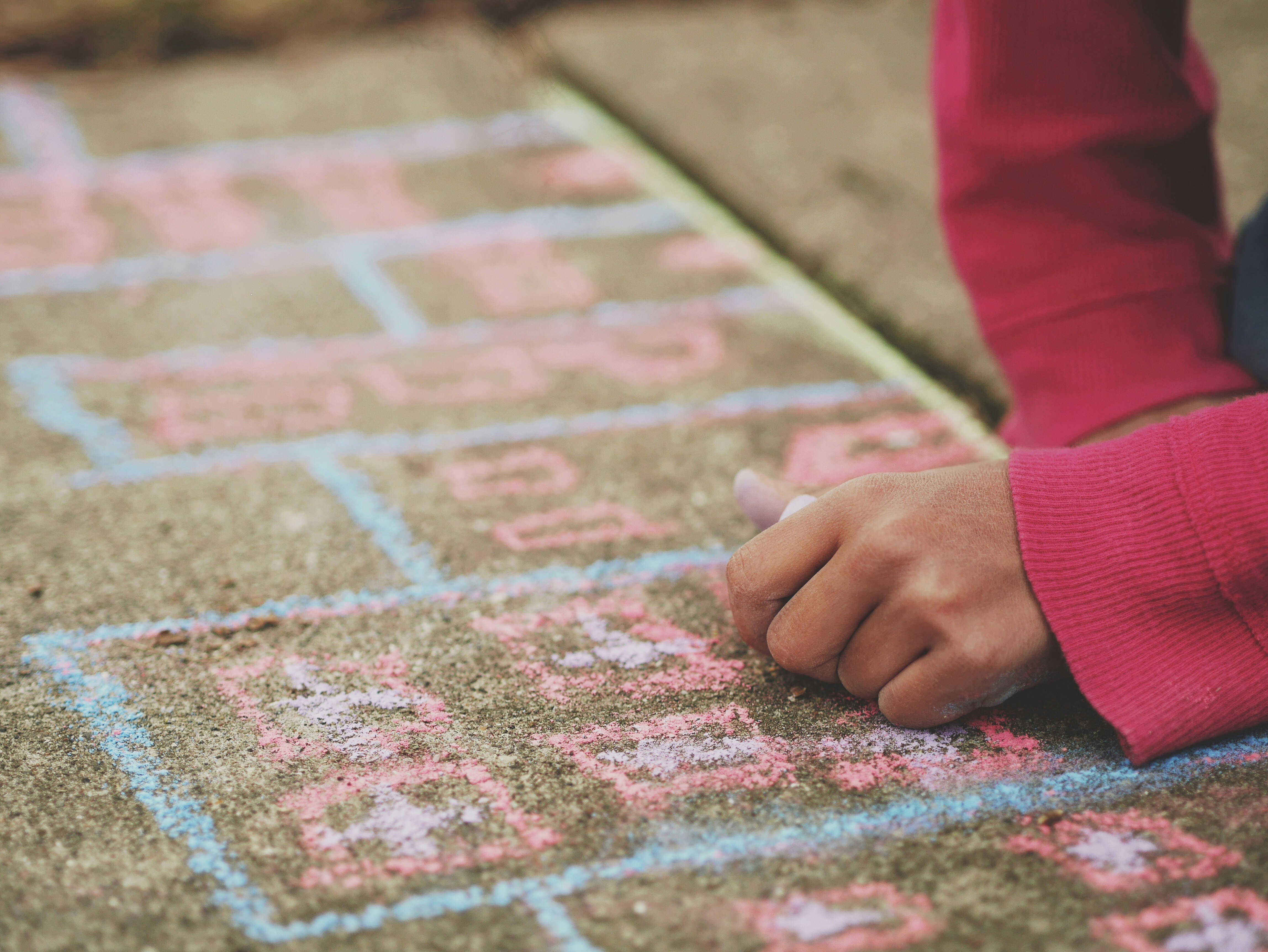 person holding chalk lying on concrete surface